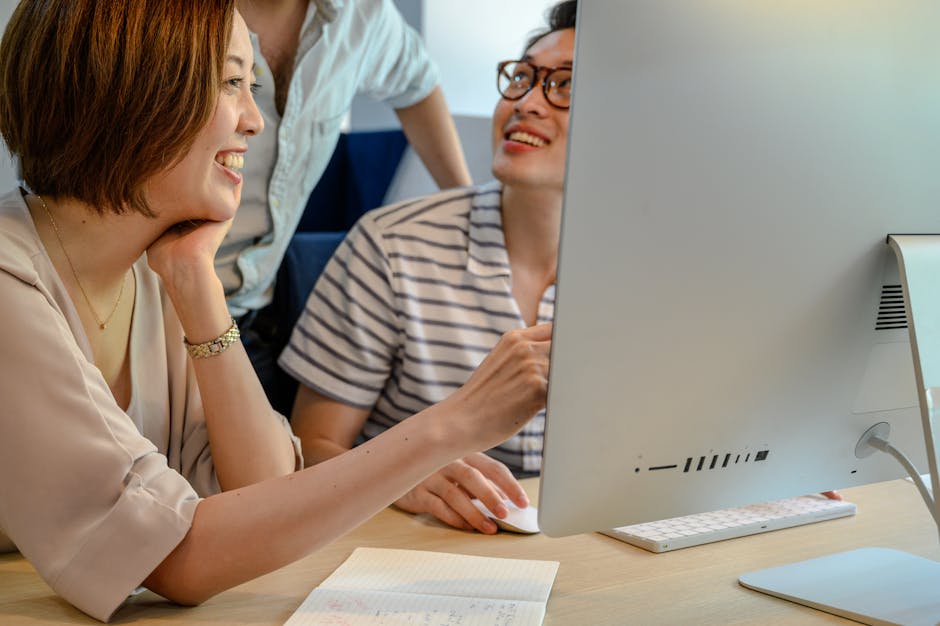 A diverse group of coworkers collaborating at a computer in a modern office environment.