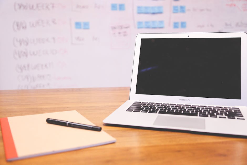 An organized workspace featuring a laptop, notepad, and pen, ideal for productivity and focus.